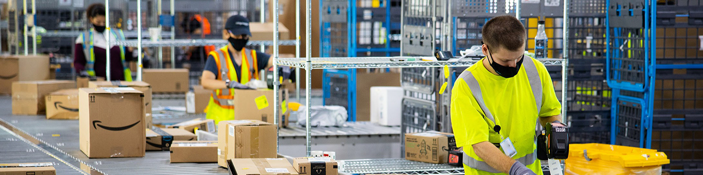 People wearing safety gear handling packages in Amazon warehouse