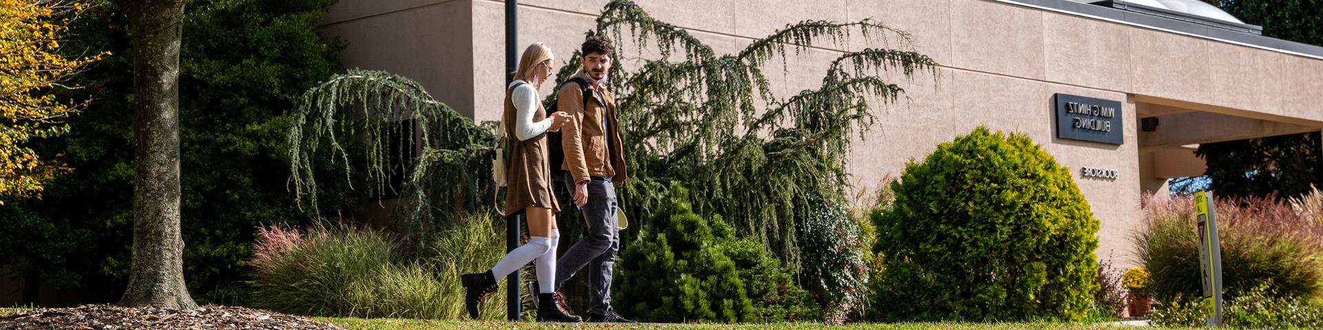 Two students walk by the outside of the Hintz Bookstore