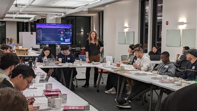 FastTrack Accelerator participants sit in Happy Valley LaunchBox powered by PNC Bank at tables with their program binders, looking at an informational screen