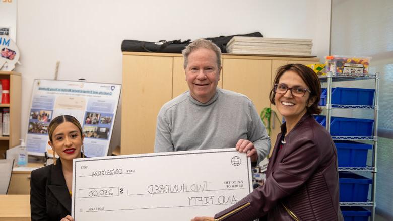 Student poses for photo with check of $250