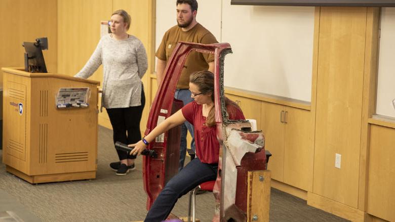 Woman sits in chair with assistive car door handle attachment 